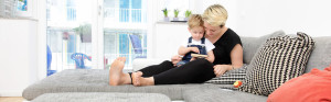 Bild på kvinna som sitter i soffa med ett barn i knät. Titel PMB Sverige bygger för IF och Trygg Hansa.
